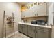 Well-organized laundry room with gray cabinets, countertop space, and a decorative ladder for hanging clothes at 4772 Se Argent Hills Ave, Pahrump, NV 89061