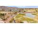 A picturesque aerial view of the golf course, with a pond, desert landscaping, and mountains in the background at 482 Bonnie Brook Pl, Henderson, NV 89012