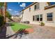 An exterior view of a backyard with a putting green, complemented by palm trees and brick pavers at 6214 Ebony Legends Ave, Las Vegas, NV 89131