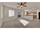 Open living area connects to a modern kitchen, featuring carpet, large windows, and a ceiling fan at 8036 Maple Park St, Las Vegas, NV 89131