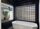 Modern bathroom featuring geometric soaking tub and glass block wall at 8112 Golfers Oasis Dr, Las Vegas, NV 89149