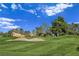 Beautiful golf course view with lush green grass, mature trees, and sand traps on a sunny day at 8112 Golfers Oasis Dr, Las Vegas, NV 89149