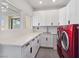 Well-lit laundry room featuring modern red washer and dryer set, white cabinetry, and quartz countertops at 8112 Golfers Oasis Dr, Las Vegas, NV 89149