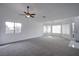 Bright living room featuring large windows, ceiling fan, and neutral carpet at 819 Teal Wing Way, Henderson, NV 89002