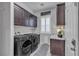 Well-organized laundry room featuring dark wood cabinetry, modern appliances, and stylish marble countertops at 9035 Chiffon Mist Ave, Las Vegas, NV 89129