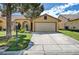 A tan house with a large garage, a well-maintained lawn, and mature landscaping at , Las Vegas, NV 89130
