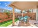 Charming covered patio with a table and chairs, complemented by artificial grass and brick accents at 10199 Rising Tree St, Las Vegas, NV 89183