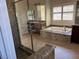 Bathroom featuring a glass-enclosed shower, soaking tub with granite surround, and wood cabinets at 12277 Bluebird Canyon Pl, Las Vegas, NV 89138