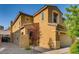 Side view of a tan two-story home featuring manicured landscaping, rock features, and a tile roof at 257 Via Franciosa Dr, Henderson, NV 89011