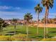 Picturesque golf course view with lush green fairways, palm trees, a pond, and mountain views in the background at 257 Via Franciosa Dr, Henderson, NV 89011