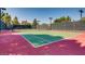 A tennis court with green playing surface, surrounded by fencing and trees at 257 Via Franciosa Dr, Henderson, NV 89011