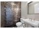 Stylish powder room features unique tiled accent wall, pedestal sink and modern fixtures at 294 Besame Ct, Las Vegas, NV 89138