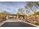 Community entrance with paved road, desert landscaping, gate and desert trees at 4273 Sunrise Flats St, Las Vegas, NV 89135