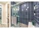 The bathroom has a gorgeous glass enclosed shower with blue subway tile and corner shelf at 4273 Sunrise Flats St, Las Vegas, NV 89135