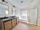 Bathroom featuring double vanity, framed mirrors, modern lighting, and a glass shower/tub combo at 4823 Jubilee Diamond Ct, Las Vegas, NV 89139