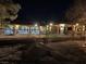 Night view of the backyard featuring illuminated patio, fountain, and wrought-iron fence, creating an inviting atmosphere at 6151 Whispering Sands Dr, Las Vegas, NV 89131