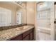 Updated bathroom features a granite countertop vanity, tiled tub, and decorative glass block window at 6151 Whispering Sands Dr, Las Vegas, NV 89131