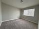 Spacious carpeted bedroom with a window, neutral paint, and a minimalist design at 6174 Meadowgrass Ln, Las Vegas, NV 89103
