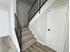 A staircase with carpeted steps, a black metal railing, and white walls with doors at 6174 Meadowgrass Ln, Las Vegas, NV 89103