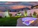 Beautiful backyard with green lawn, cozy fire pit, and privacy wall at twilight at 6655 Tranquil Seas Ct, Las Vegas, NV 89139