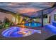 Custom backyard boasts a beautiful pool, waterfall feature, covered bar, and cozy fire pit at twilight at 6655 Tranquil Seas Ct, Las Vegas, NV 89139