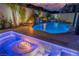 Custom backyard boasts a beautiful pool, waterfall feature, and cozy fire pit at twilight at 6655 Tranquil Seas Ct, Las Vegas, NV 89139