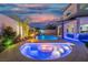Custom backyard boasts a beautiful pool, waterfall feature, covered bar, and cozy fire pit at twilight at 6655 Tranquil Seas Ct, Las Vegas, NV 89139