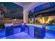 Outdoor kitchen area with a built-in grill, mini-fridge, stone accents, and blue ambient lighting at 6655 Tranquil Seas Ct, Las Vegas, NV 89139