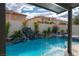 Sparkling backyard pool with rock waterfall, covered patio, and a view of the neighborhood at 6655 Tranquil Seas Ct, Las Vegas, NV 89139