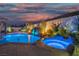 Stunning backyard pool featuring a rock waterfall, spa, and ambient lighting for evening relaxation at 6655 Tranquil Seas Ct, Las Vegas, NV 89139