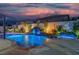 Inviting backyard pool with rock waterfall feature, vibrant lighting, and ample patio space at 6655 Tranquil Seas Ct, Las Vegas, NV 89139