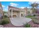 A covered back patio features a view of a green lawn and lush landscaping with blue sky and white clouds at 8512 Porch Rocker St, Las Vegas, NV 89143
