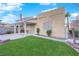 A backyard featuring a well-maintained lawn, covered patio, and block wall fencing, offering privacy and space at 8512 Porch Rocker St, Las Vegas, NV 89143