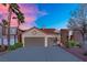 The exterior of this home features a two car garage, desert landscaping, and palm trees at 8512 Porch Rocker St, Las Vegas, NV 89143