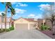The exterior of this home features a two car garage, desert landscaping, and palm trees at 8512 Porch Rocker St, Las Vegas, NV 89143