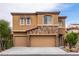 Charming home with a tan stucco exterior, stone accents, three-car garage, and well-maintained landscaping at 9869 White Lilac St, Las Vegas, NV 89178