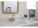 Modern bathroom vanity with white countertop, gold fixtures, and a rattan-framed mirror at 10420 Luella Ct, Las Vegas, NV 89143