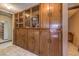 Hallway featuring a custom wooden cabinet with display cases and tiled flooring at 10615 Rancho Destino Rd, Las Vegas, NV 89183