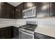 Kitchen with stainless steel oven, microwave, and dark cabinets at 3158 Teaderman Walk, Henderson, NV 89044
