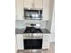 Kitchen features a stainless steel range, microwave, white cabinets, and decorative backsplash at 3805 Carisbrook Dr, North Las Vegas, NV 89081