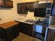 Close up view of the kitchen features dark cabinetry, laminate countertops, stainless steel sink, and a stove at 3967 Visby Ln, Las Vegas, NV 89119