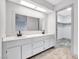 Bathroom featuring double sinks, white cabinets and a view of the walk-in closet at 5815 Christchurch Ave, Las Vegas, NV 89110