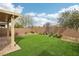 A backyard features an artificial lawn, a covered patio, a brick trim, and various trees at 6622 Palm Branch St, North Las Vegas, NV 89086