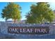 Stone sign with 'Oak Leaf Park' lettering, nestled among trees, marking the entrance to a serene outdoor community space at 6690 Interstellar St, Las Vegas, NV 89135