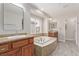 Bathroom with a soaking tub with tile surround and dual vanity with wood cabinets at 6712 Biltmore Garden St, Las Vegas, NV 89149