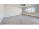 Large bedroom with gray carpet, a ceiling fan, and a large window overlooking the neighborhood at 7900 Holly Knoll Ave, Las Vegas, NV 89129