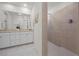 Bright bathroom featuring double sinks, white cabinets, and a walk-in shower with beige tile at 8106 Skye Glen St, Las Vegas, NV 89166