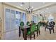 Inviting dining area with large windows, a decorative chandelier, and dark wooden table with stylish green chairs at 8390 Carmel Ridge Ct, Las Vegas, NV 89113