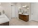 This bathroom is furnished with double sinks, a dark wood cabinet and tile flooring, as well as white doors at 9930 Zakos Ct, Las Vegas, NV 89149