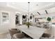 Open-concept dining room features modern chandelier and table for six, seamlessly connecting to the cozy living area at 9930 Zakos Ct, Las Vegas, NV 89149